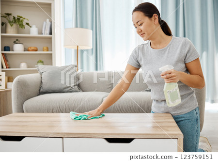 Cleaning table, bottle and Asian woman working to keep her living room clean in home, spray for clean desk and happy with product results. Cleaner with housekeeping service job in apartment lounge 123759151