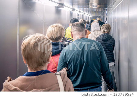 A Queue of People in the Airport Boarding Tunnel, embodying the spirit of travel and anticipation, People, passengers in a queue, walk along a telescopic ramp arm to board a flight. 123759554