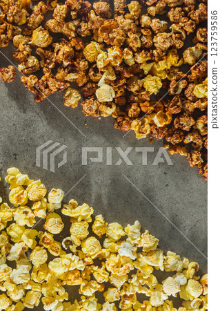 A top down photograph designed for a poster, featuring two distinct flavors of popcorn, caramel and classic salted arranged in separate sections, one on the top and the other on the bottom. 123759586