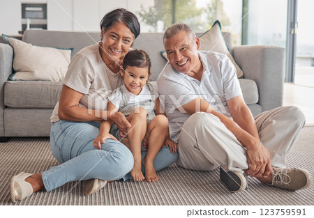 Girl, hug and grandparents with love, care and relax in family home together. Portrait of happy child, smile senior grandma and laugh elderly grandpa bond and play together in the living room floor Girl, hug and grandparents with love, care and relax in family home together. Portrait of happy child, smile senior grandma and laugh elderly grandpa bond and play together in the living room floor 123759591