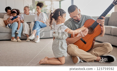 Father, child and guitar teaching, learning or music in the living room with family in the background. Girl and man play with a musical instrument together bonding in the house with creative hobby Father, child and guitar teaching, learning or music in the living room with family in the background. Girl and man play with a musical instrument together bonding in the house with creative hobby 123759592