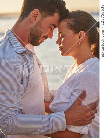 Couple, sunset and beach for love together on holiday or honeymoon. Man, woman and ocean in embrace for romance, during vacation, trip or travel by the sea in late summer sunlight show happiness 123759638