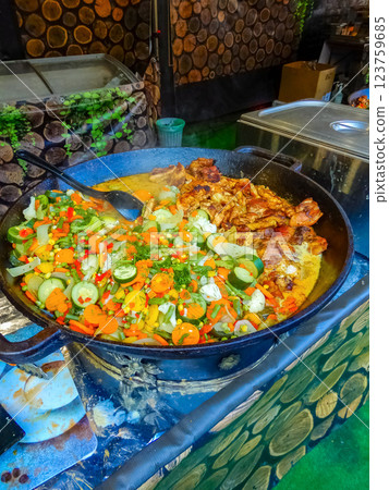 skillet filled with colorful vegetables and meat cooking outdoors, street food . High quality photo 123759685