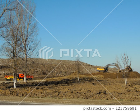 construction equipment working on a mound of earth, an excavator and a bulldozer in the process of leveling a site or filling a pit or developing the land 123759691