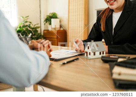 Businesswoman embraces client after successful property negotiation. 123760011