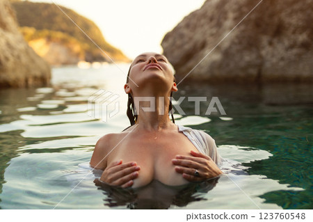Nude sexy woman in water at sunset. Beautiful blonde woman with short wet hair and big breasts, art portrait in sea Nude sexy woman in water at sunset. Beautiful blonde woman with short wet hair and big breasts, art portrait in sea 123760548