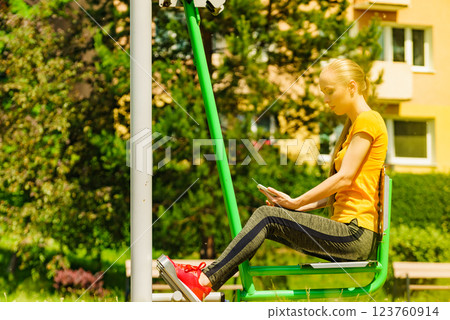 Girl doing exercises outdoor, holding phone 123760914