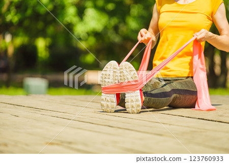 Girl doing exercise outdoor, using resistance fit band. 123760933