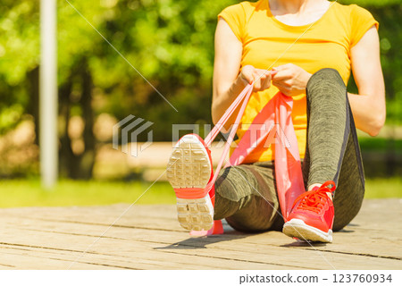 Girl doing exercise outdoor, using resistance fit band. 123760934