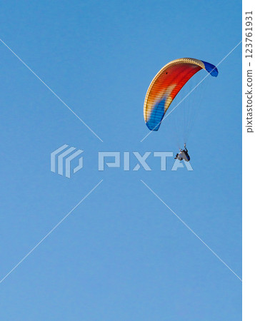 Paraglider flying in blue sky. 123761931