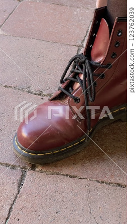 A foot in a raspberry boot on pink paving slabs A foot in a raspberry boot on pink paving slabs 123762039