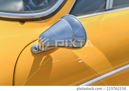 Close up yellow vintage car chrome rusty rearview side mirror 123762238