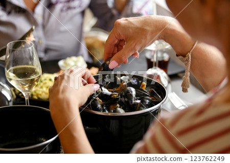 Woman's hands holding mussels over a pan of mussels in a fish restaurant Woman's hands holding mussels over a pan of mussels in a fish restaurant 123762249
