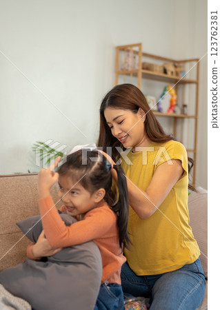 Lovely mom and little young daughter spending time together in their living room. 123762381