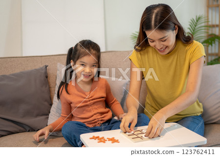 Lovely mom and little young daughter spending time together in their living room. Lovely mom and little young daughter spending time together in their living room. 123762411
