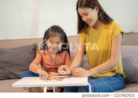 Lovely mom and little young daughter spending time together in their living room. Lovely mom and little young daughter spending time together in their living room. 123762423