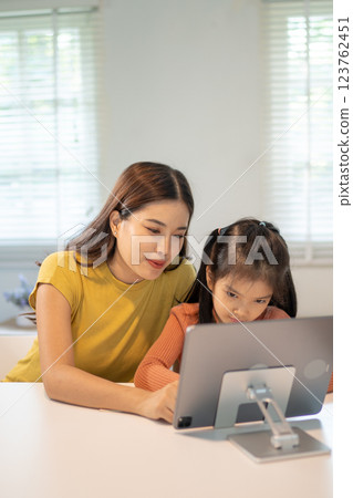 Lovely mom and little young daughter spending time together in their living room. Lovely mom and little young daughter spending time together in their living room. 123762451