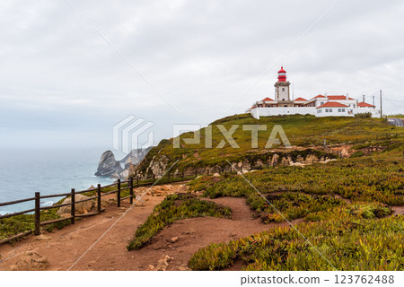 Iconic lighthouse sits atop the cliffs of Cape Roca, Portugal, on an overcast day. 123762488