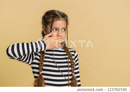 Frightened child girl closing mouth with hands refusing to tell terrible secret, unbelievable truth Frightened child girl closing mouth with hands refusing to tell terrible secret, unbelievable truth 123762590