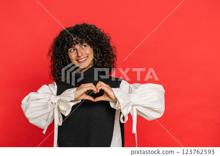 Smiling young woman makes heart gesture demonstrates love sign expresses good feelings and sympathy 123762593