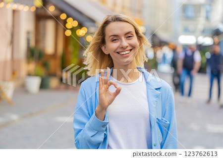 Young woman looking approvingly at camera showing OK gesture positive like sign Okay celebrate win 123762613