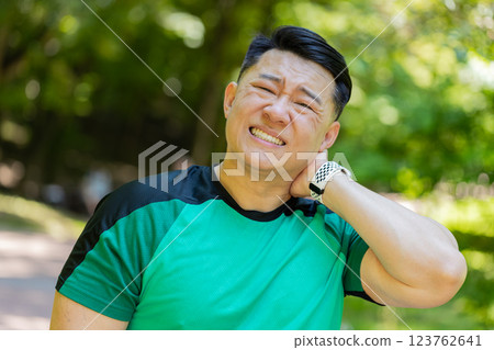 Asian man have shoulder neck joints pain, sport injury concept after running in park outdoors Asian man have shoulder neck joints pain, sport injury concept after running in park outdoors 123762641