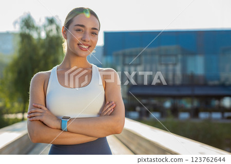 Portrait of happy Caucasian young sporty woman in activewear standing arms crossed in city park Portrait of happy Caucasian young sporty woman in activewear standing arms crossed in city park 123762644