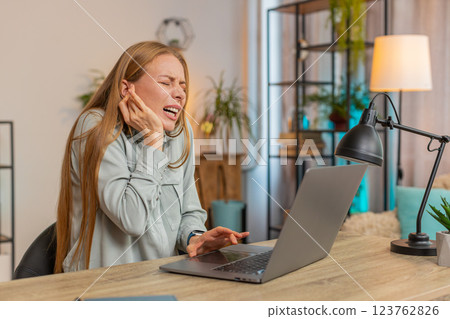 Sick Caucasian mature woman freelancer sitting at home office table feeling ear pain in living room 123762826