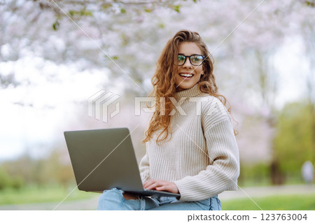 Happy female freelancer sitting in the office with a laptop. Nature and urban lifestyle concept. Happy female freelancer sitting in the office with a laptop. Nature and urban lifestyle concept. 123763004