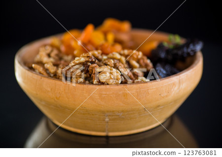 Prunes, dried apricots and nuts in a wooden bowl on a dark background 123763081