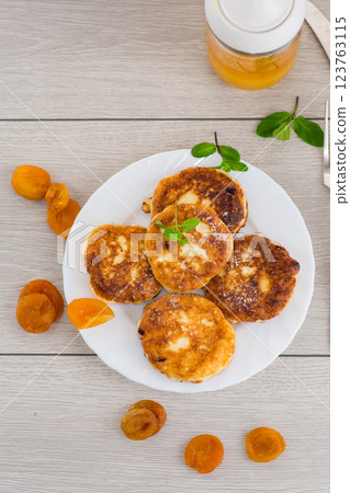 Fresh cottage cheese pancakes with pieces of dried apricots and a leaf of mint 123763115