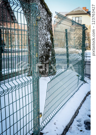 Damaged Metal Fence in a Snowy Urban Setting Damaged Metal Fence in a Snowy Urban Setting 123763427
