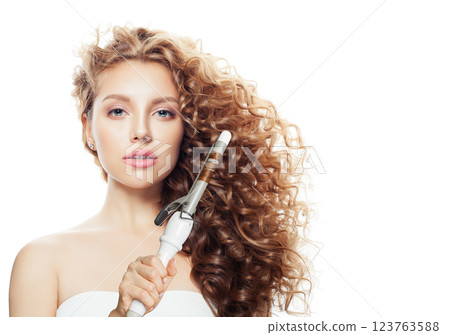 Elegant brunette model using curling iron on white background. Elegant brunette model using curling iron on white background. 123763588