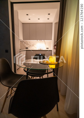 Apartment Kitchen Dining Modern Interior Design: Evening ambiance, glass table, minimalist decor. Apartment Kitchen Dining Modern Interior Design: Evening ambiance, glass table, minimalist decor. 123764190