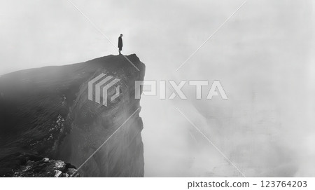 Person Standing on Foggy Mountain Cliff Creating a Dramatic Landscape Scene 123764203