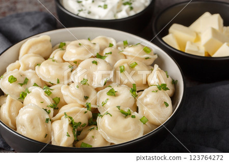 Pelmeni dumplings filled minced meat served with sour cream, butter and herbs close-up. Horizontal Pelmeni dumplings filled minced meat served with sour cream, butter and herbs close-up. Horizontal 123764272
