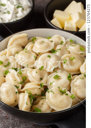 Russian pelmeni dumplings with sour cream, butter and herbs close-up. Vertical 123764275