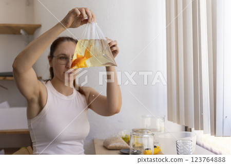 Woman holding plastic bag with goldfish and preparing new fish tank 123764888