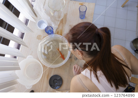 Woman looking at goldfish in plastic bowl on table 123764890