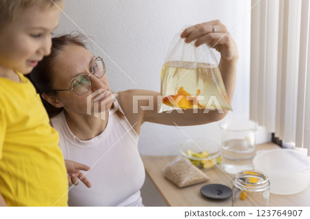 Mother showing goldfish in plastic bag to child at home 123764907