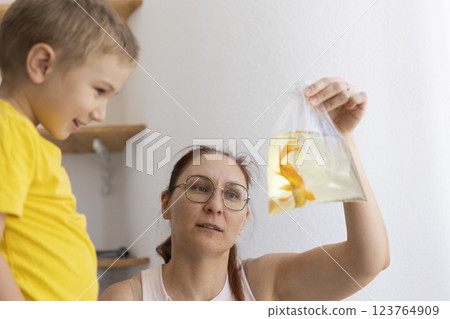 Mother showing goldfish in plastic bag to child Mother showing goldfish in plastic bag to child 123764909