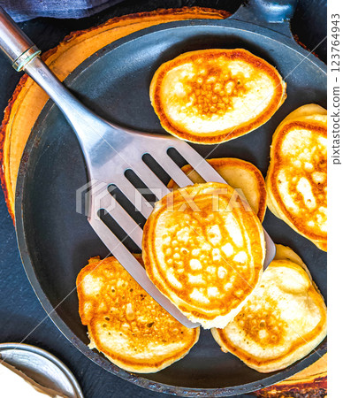 Small pancakes in a pan on a wooden board Small pancakes in a pan on a wooden board 123764943