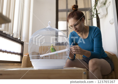 Woman changing water in bird cage at home 123765167
