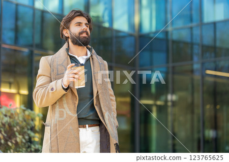 Happy Indian business man tourist enjoying morning coffee hot drink walking on city downtown street Happy Indian business man tourist enjoying morning coffee hot drink walking on city downtown street 123765625