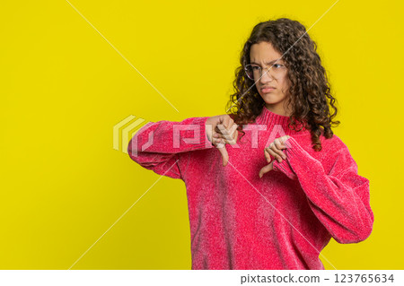 Upset girl teen child showing thumbs down gesture disapproval dissatisfied dislike negative feedback Upset girl teen child showing thumbs down gesture disapproval dissatisfied dislike negative feedback 123765634
