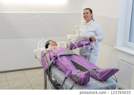 Cosmetology therapist doctor making pressotherapy procedure treatment for woman in a beauty salon Cosmetology therapist doctor making pressotherapy procedure treatment for woman in a beauty salon 123765635
