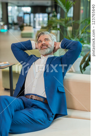 Caucasian businessman taking break leaning on couch after working celebrating success at hotel lobby Caucasian businessman taking break leaning on couch after working celebrating success at hotel lobby 123765640