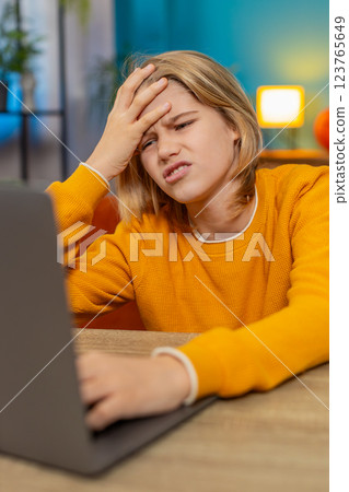 Teenager boy frustrated playing difficult video game on laptop, banging keyboard on couch at home 123765649