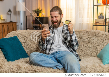 Young man paying with credit card at home, phone purchase, sofa check, nod ok, confident secure vibe 123765665