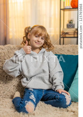 Young teenager girl showing thumbs up with a happy expression and positive attitude indoors at home Young teenager girl showing thumbs up with a happy expression and positive attitude indoors at home 123765668
